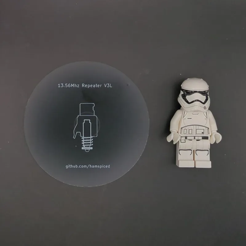 62mm repeater disc marked ‘13.56MHz Repeater V3L’ beside a LEGO stormtrooper minifigure for scale