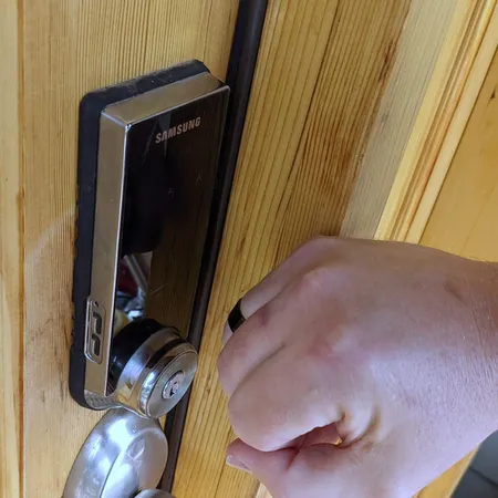 Hand wearing the Magic Ring held against a Samsung smart door lock