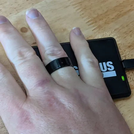 Magic Ring worn on a finger being read by a black desktop RFID reader