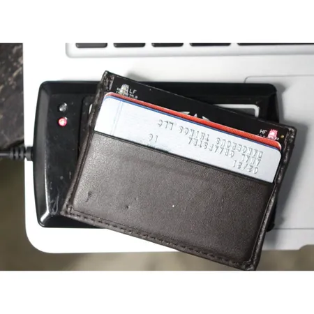 Wallet holding the RFID Diagnostic Card held against a black desktop reader to test field strength