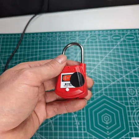 Red RFID padlock held in one hand after a repeater sticker was applied to extend read range