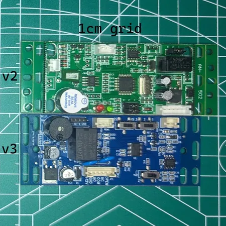 xEM Access Controller v2 (green) and v3 (blue) boards side by side on a 1cm grid for size comparison