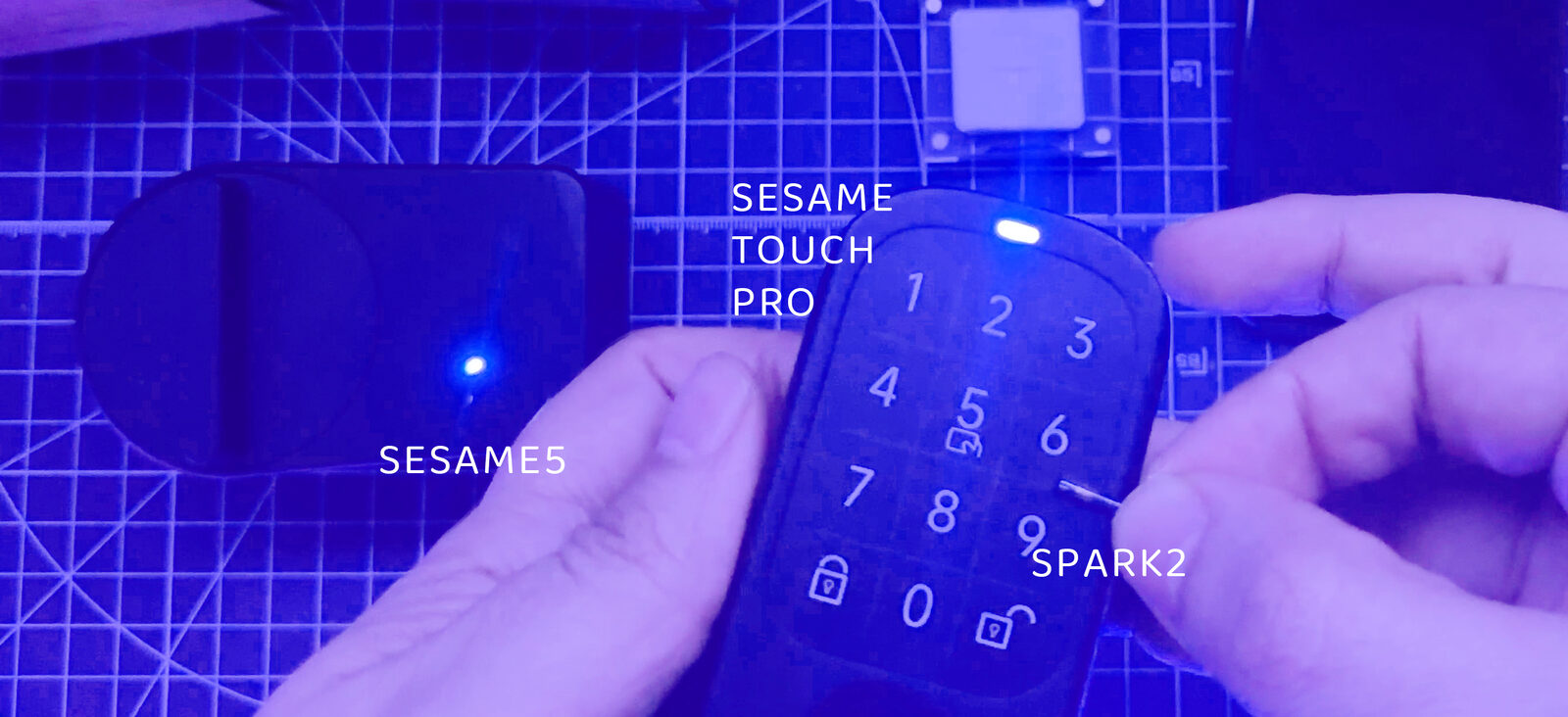 カッティングマットの上に置いたCandy Houseのロック2台。Sesame 5とSesame Touch Pro。Touch Proの読み取り部にSpark 2をかざし、ランプが点灯している様子